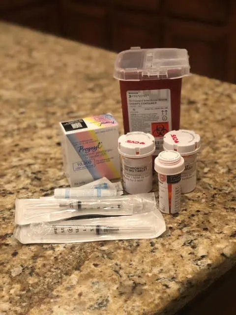 Fertility Drugs and Shots on a tan granite kitchen counter.