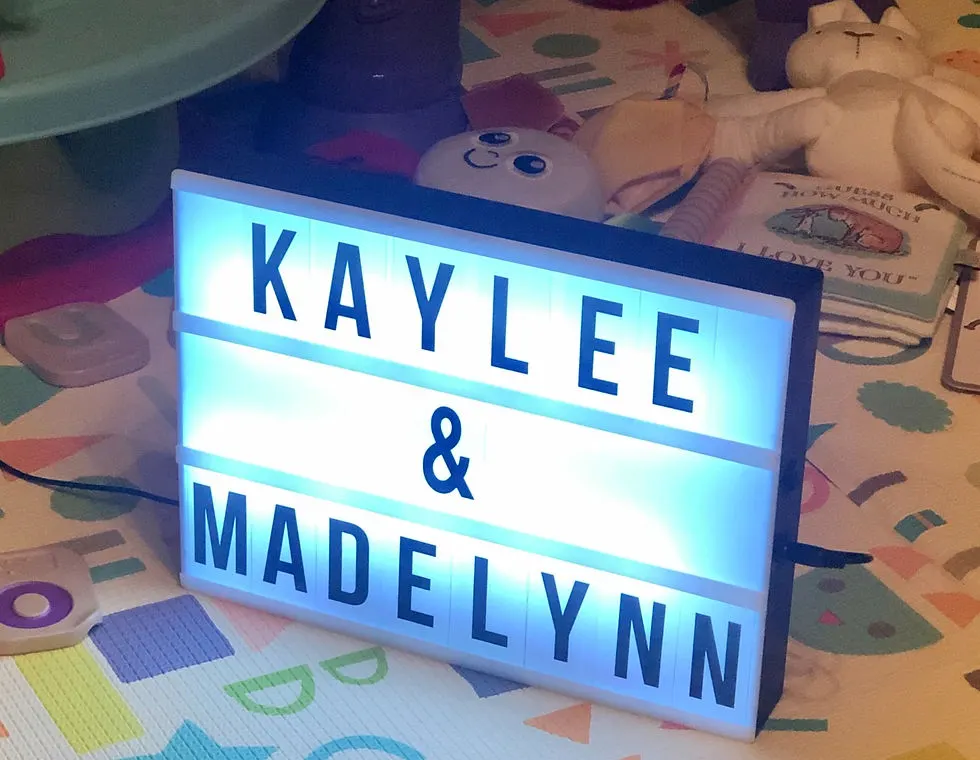 A bright white light box with black letters in print that read "Kaylee & Madelynn"